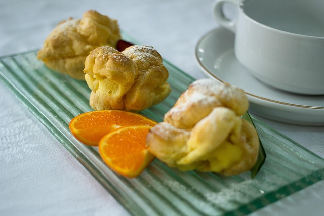 Freshly baked cream puffs dusted with powdered sugar on a serving plate