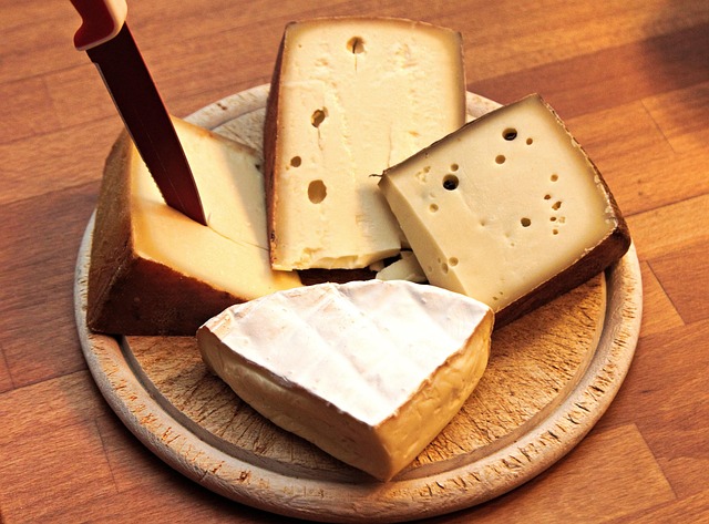 A wedge of aged hard cheese with crystals, being wrapped correctly in paper.