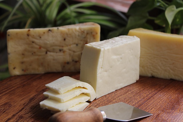 A variety of cheeses, including hard and soft types, arranged on a wooden board.