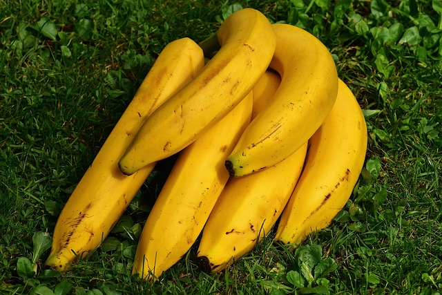 A bunch of fresh yellow bananas hanging from a hook.