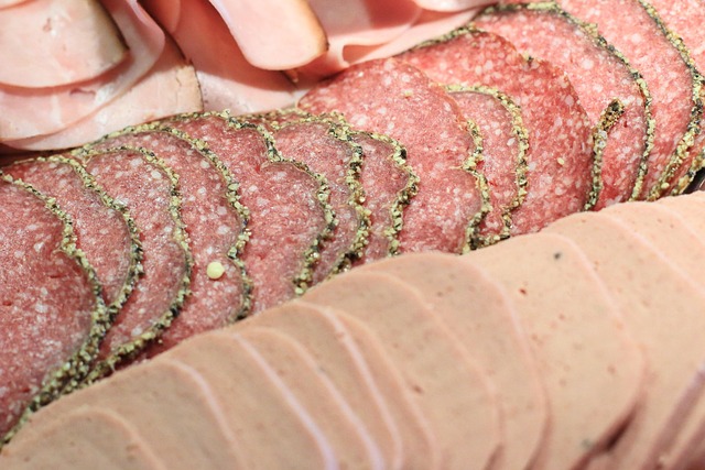 Sliced deli meat including turkey, ham and salami stored in an airtight container in the fridge